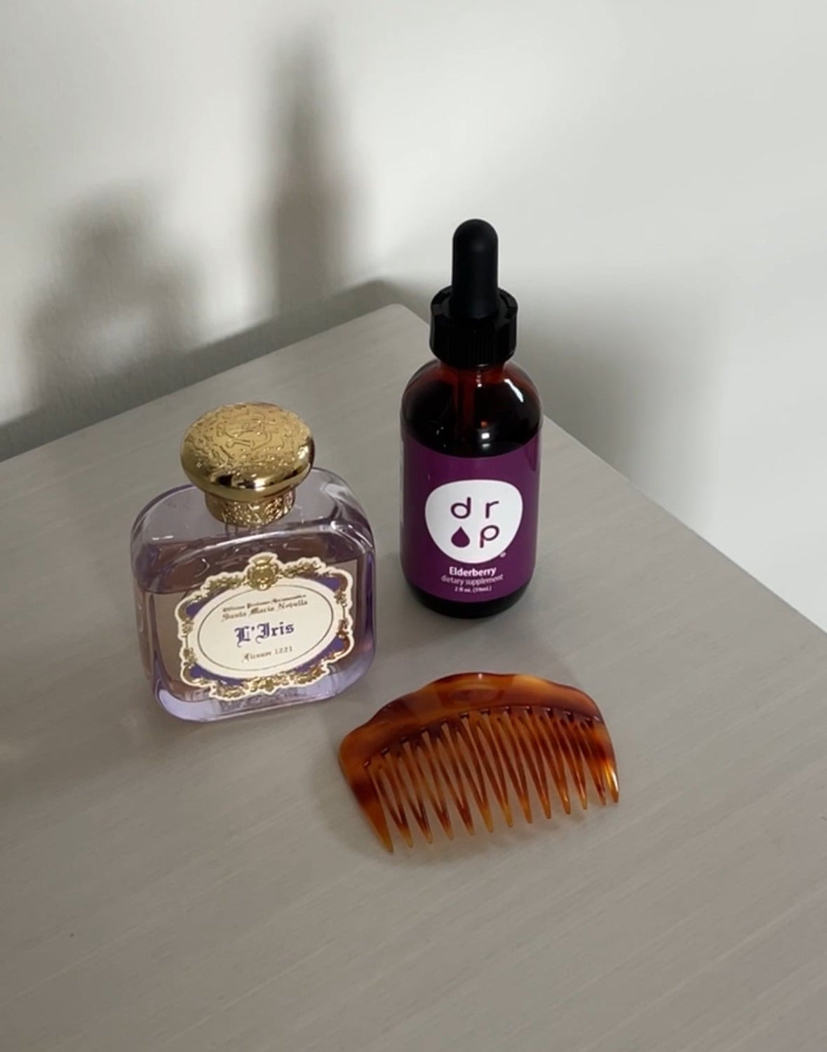 Three items: a small bottle, a dropper bottle, and a comb on a light surface with a white background.